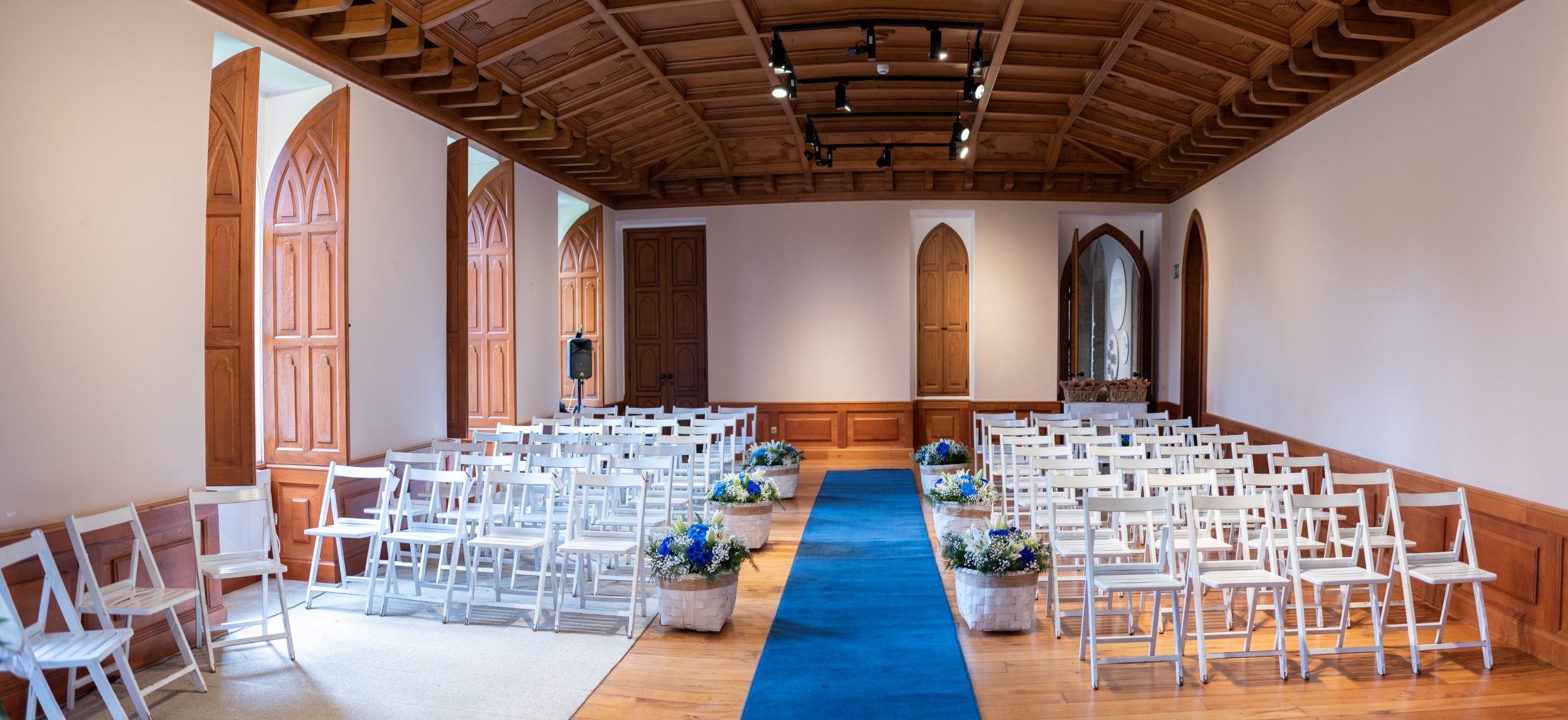 Salón vacío preparado para ceremonias con sillas y flores